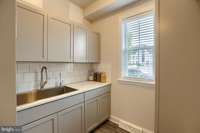 kitchen with gray cabinetry, sink, backsplash, and dark hardwood / wood-style floors