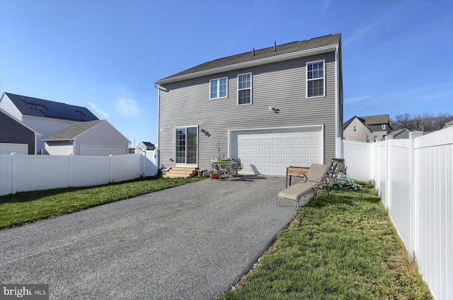 back of property featuring a garage and a lawn