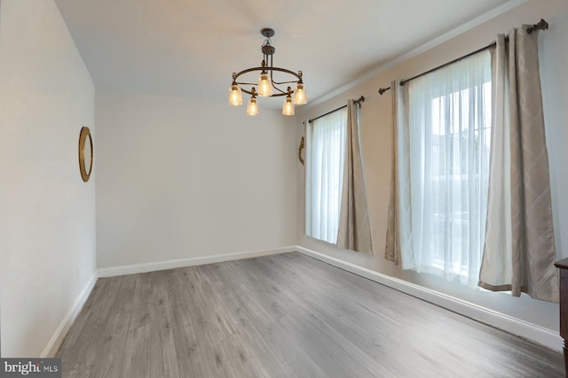 spare room with a chandelier and light hardwood / wood-style floors