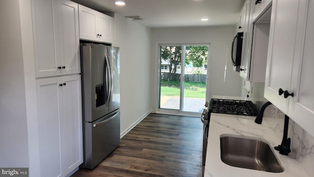 kitchen with white cabinetry, light stone counters, dark hardwood / wood-style flooring, appliances with stainless steel finishes, and sink