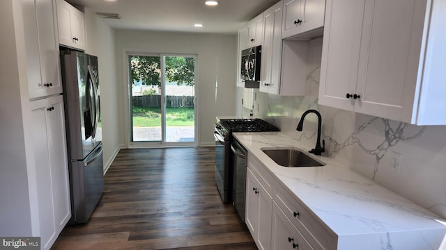 kitchen featuring white cabinets, dark wood-type flooring, light stone counters, stainless steel appliances, and sink