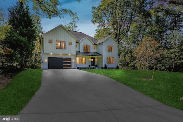 view of front facade with concrete driveway, a lawn, an attached garage, board and batten siding, and a standing seam roof