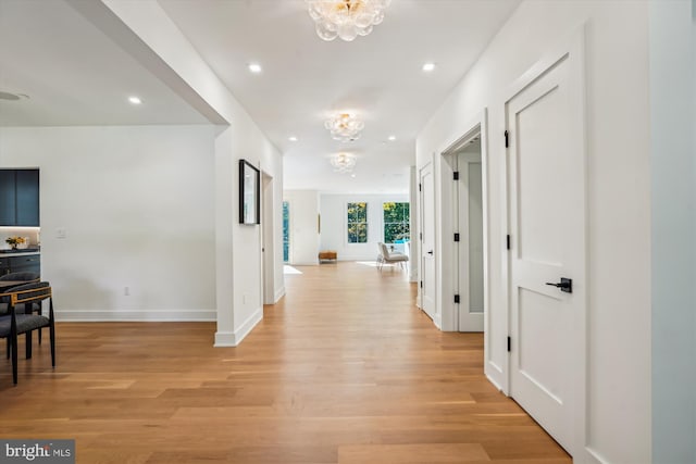 corridor featuring light hardwood / wood-style flooring and a chandelier