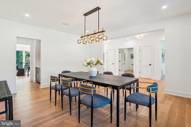 dining area featuring light wood-type flooring and an inviting chandelier