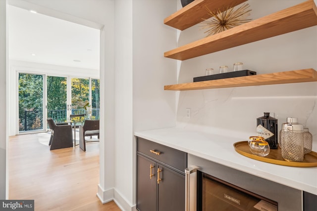 bar featuring beverage cooler and light hardwood / wood-style floors