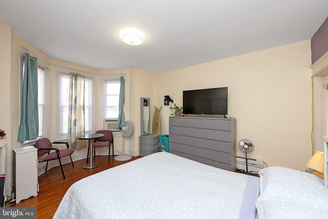 bedroom featuring dark wood-type flooring, baseboard heating, and cooling unit