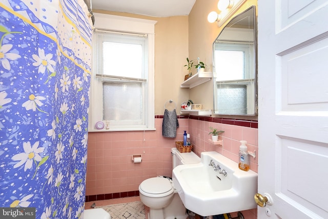 bathroom featuring tile patterned flooring, tile walls, toilet, and a healthy amount of sunlight