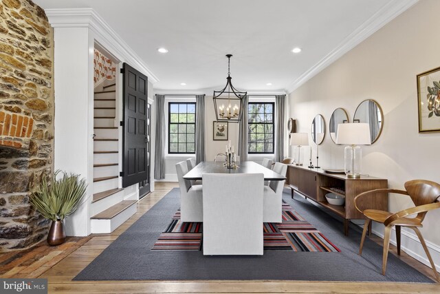 dining space with wood-type flooring, crown molding, and a chandelier