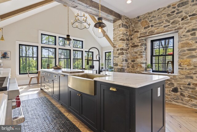 kitchen with sink, decorative light fixtures, a kitchen island with sink, light parquet flooring, and beam ceiling