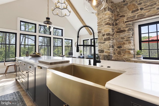 kitchen with beam ceiling, a notable chandelier, decorative light fixtures, sink, and high vaulted ceiling