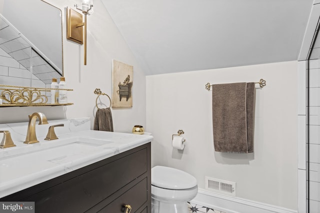 bathroom featuring vanity, lofted ceiling, and toilet