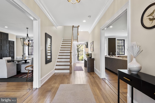 foyer featuring an inviting chandelier, crown molding, and light wood-type flooring