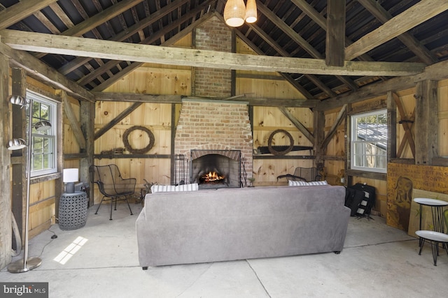 living room with vaulted ceiling, a brick fireplace, and brick wall