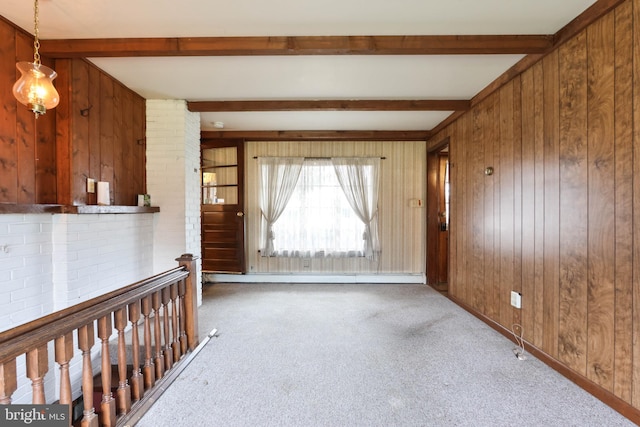 carpeted empty room with beamed ceiling and wooden walls