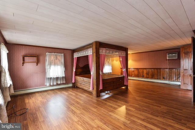 unfurnished bedroom featuring hardwood / wood-style flooring, a baseboard heating unit, and an AC wall unit