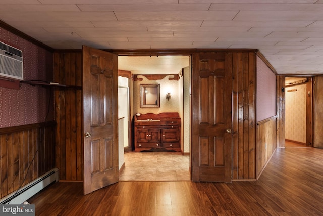 interior space with wooden walls, baseboard heating, and hardwood / wood-style flooring