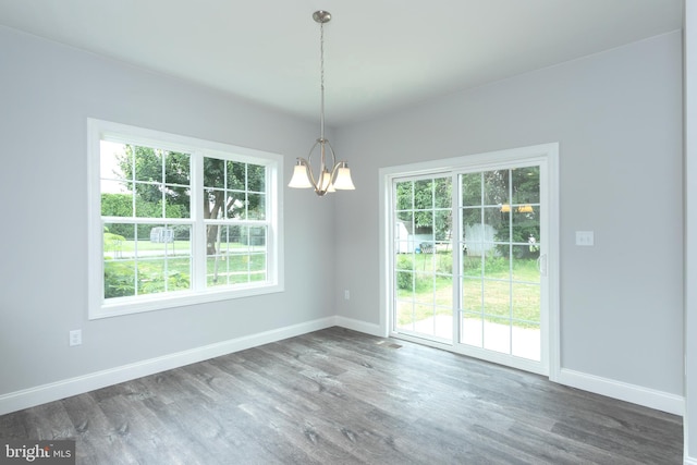 unfurnished dining area with dark hardwood / wood-style flooring and a chandelier