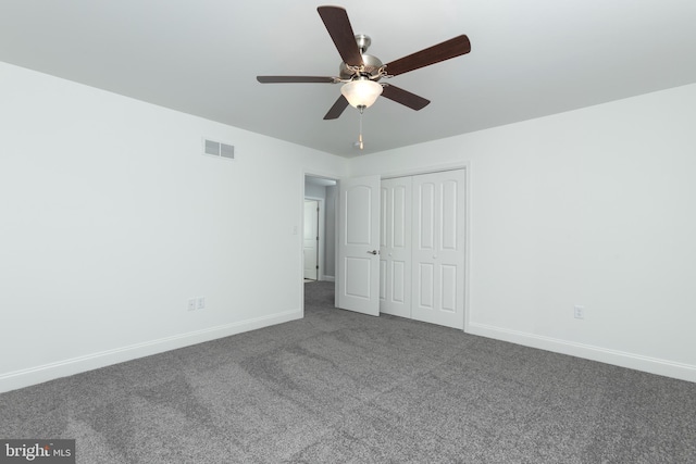 unfurnished bedroom with ceiling fan, dark carpet, and a closet