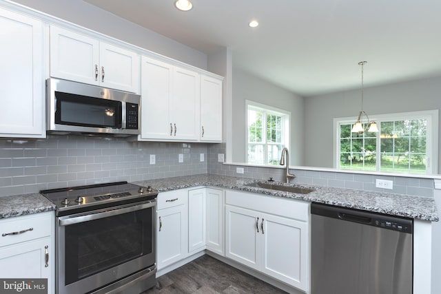 kitchen with sink, white cabinetry, stainless steel appliances, light stone countertops, and decorative backsplash