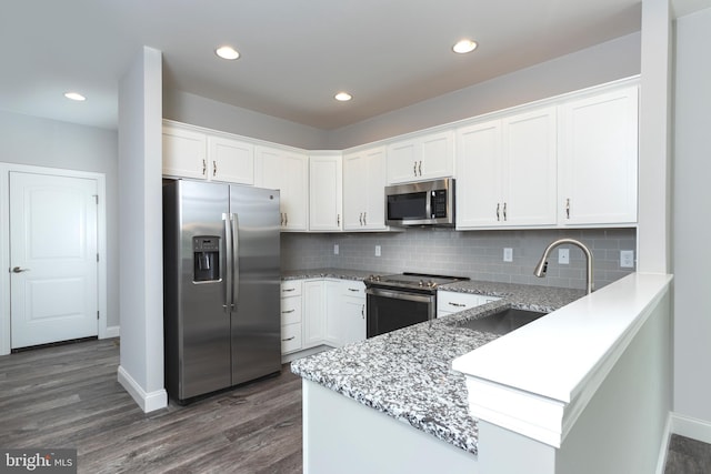 kitchen with sink, light stone countertops, white cabinets, and appliances with stainless steel finishes