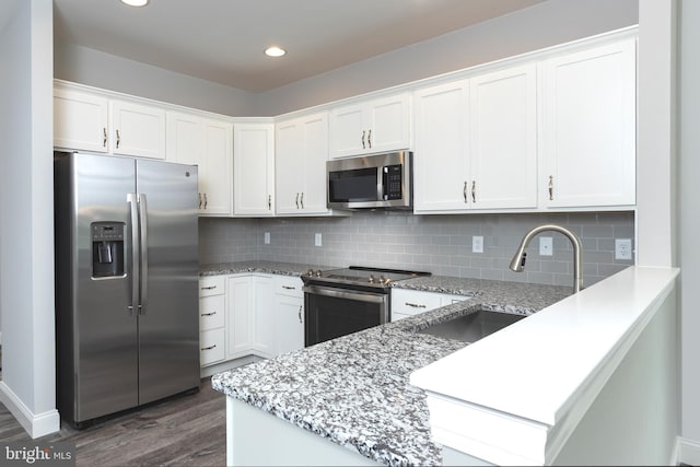 kitchen featuring appliances with stainless steel finishes, dark hardwood / wood-style floors, white cabinetry, sink, and light stone counters