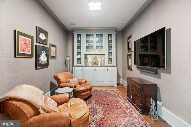 sitting room featuring crown molding, indoor bar, and dark hardwood / wood-style flooring