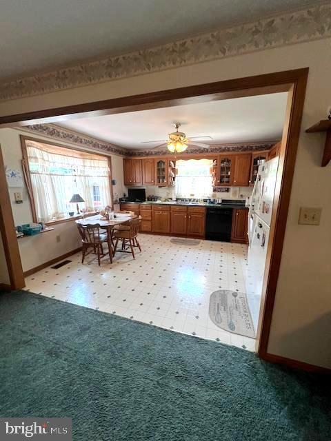 kitchen with white fridge, black dishwasher, light colored carpet, and ceiling fan