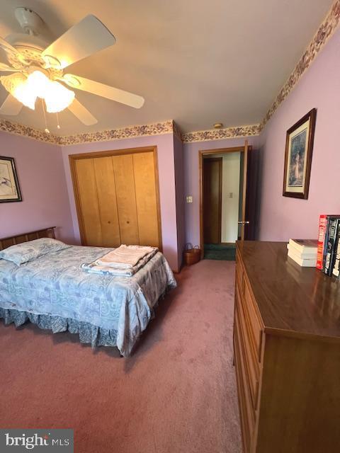 carpeted bedroom with ceiling fan and a closet