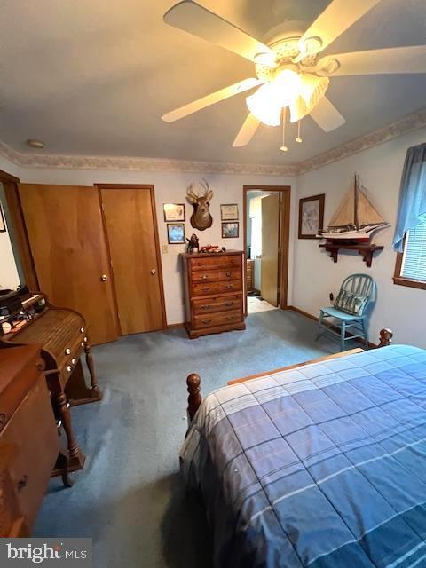 bedroom featuring light colored carpet, ornamental molding, and ceiling fan