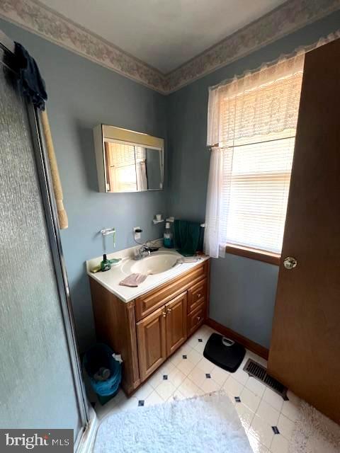 bathroom featuring vanity, crown molding, and a shower with shower door