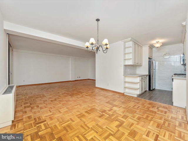 interior space featuring a notable chandelier, open shelves, light countertops, appliances with stainless steel finishes, and white cabinets