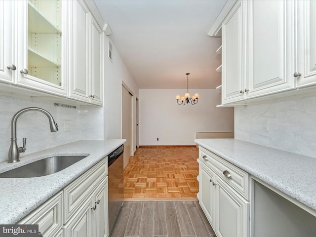 kitchen with dishwasher, a chandelier, white cabinets, and a sink