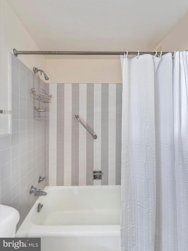 bathroom featuring shower / tub combo and toilet