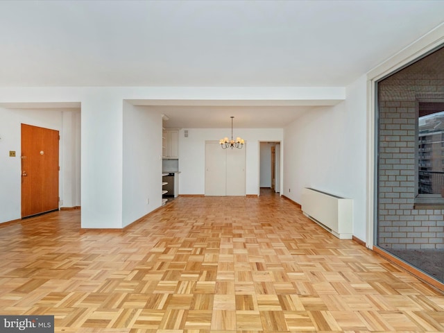 empty room with radiator, an inviting chandelier, and baseboards
