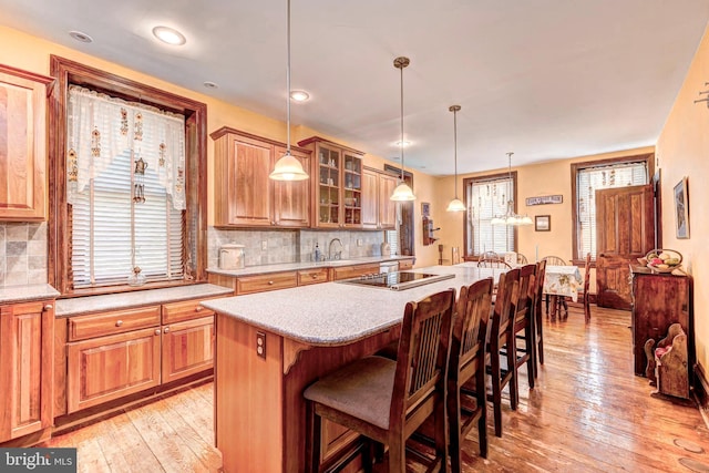 kitchen featuring backsplash, light wood-type flooring, and a breakfast bar