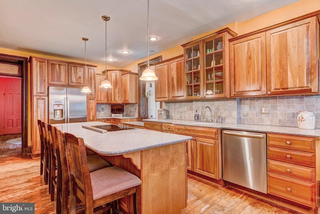 kitchen with appliances with stainless steel finishes, sink, decorative backsplash, and light hardwood / wood-style floors