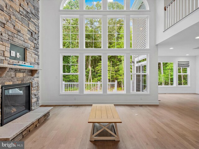 unfurnished living room with a high ceiling, a fireplace, and light hardwood / wood-style flooring