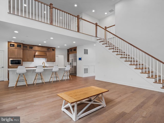 unfurnished living room with a towering ceiling and light hardwood / wood-style floors