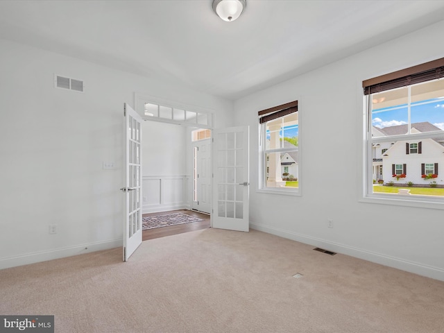 carpeted spare room featuring french doors