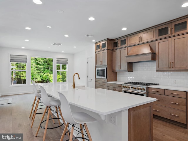 kitchen with built in microwave, a spacious island, a breakfast bar area, high end range, and custom range hood