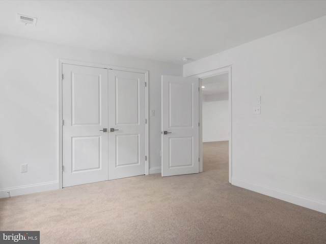 unfurnished bedroom featuring light colored carpet and a closet