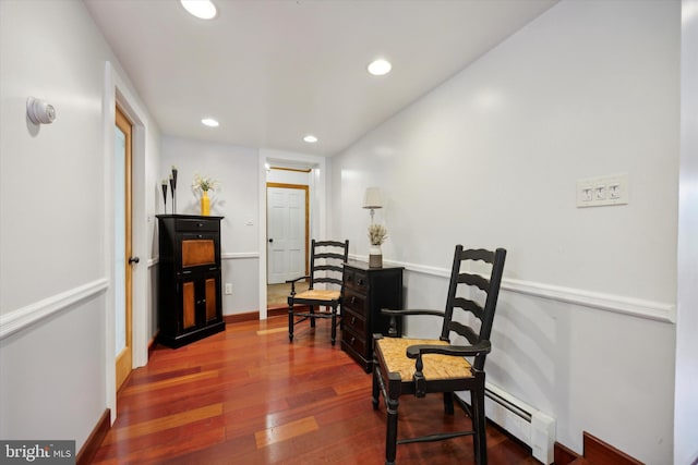 living area featuring baseboard heating and hardwood / wood-style flooring