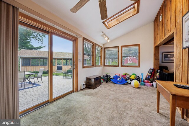 playroom with vaulted ceiling with skylight, carpet flooring, and a baseboard heating unit