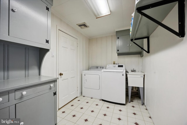 laundry room featuring crown molding, sink, washing machine and clothes dryer, and cabinets