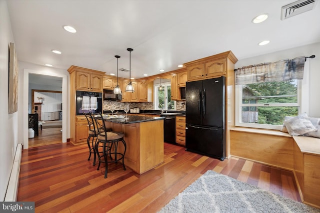 kitchen featuring baseboard heating, black appliances, a kitchen island, and dark hardwood / wood-style flooring