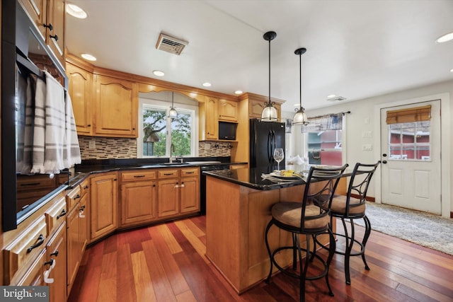 kitchen featuring pendant lighting, a center island, black fridge, and dark hardwood / wood-style flooring