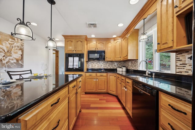 kitchen featuring hanging light fixtures, sink, black appliances, light hardwood / wood-style floors, and decorative backsplash