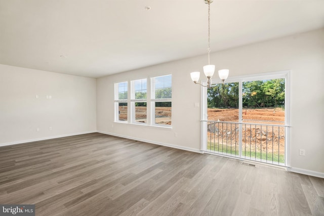 unfurnished room with hardwood / wood-style floors and a chandelier