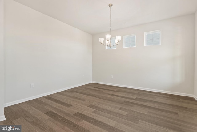 spare room with dark hardwood / wood-style flooring and a notable chandelier