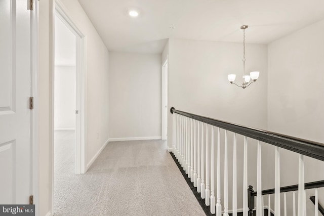 corridor featuring light colored carpet and a notable chandelier